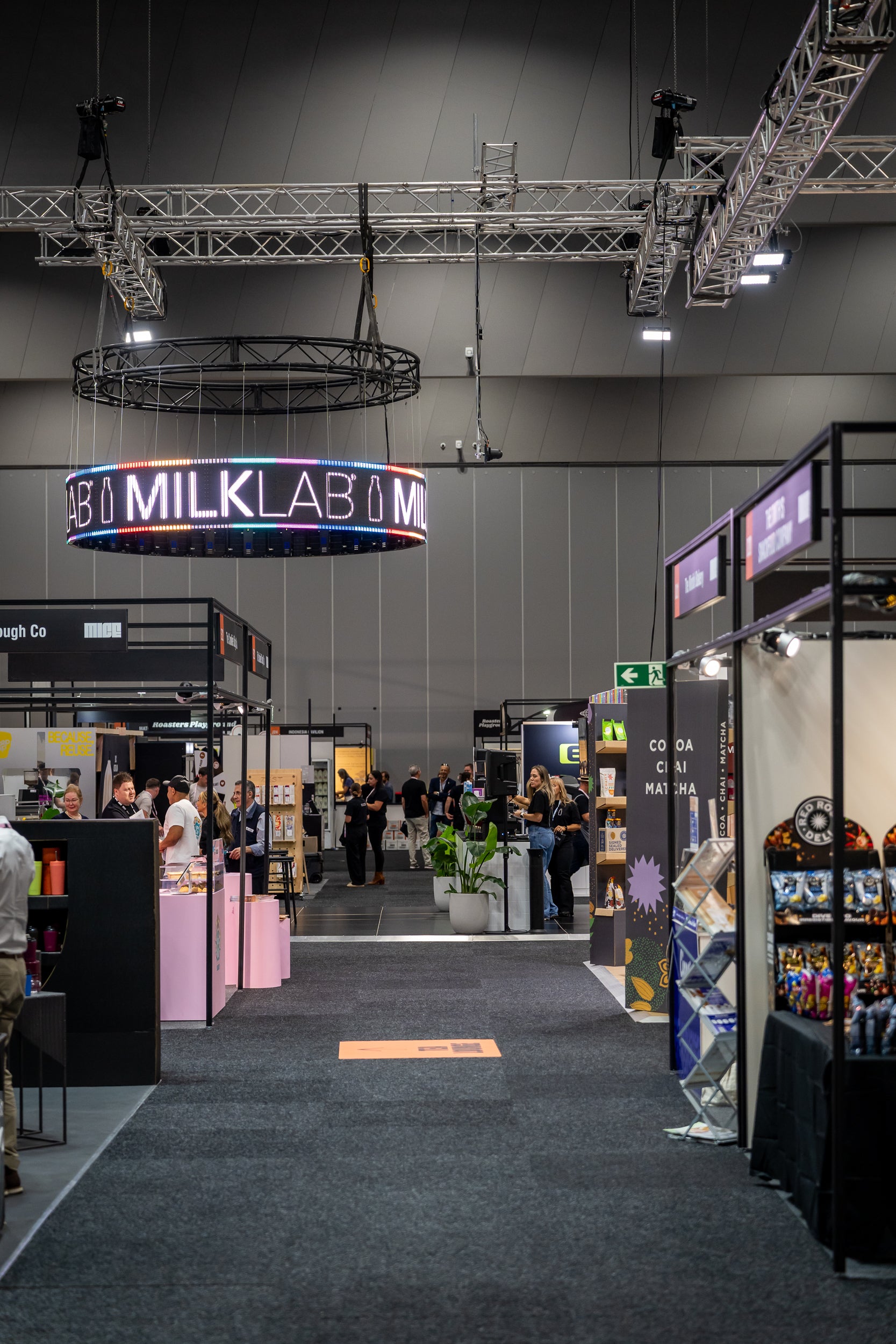 Exhibition hall with 'MILKLAB' sign and various booths.