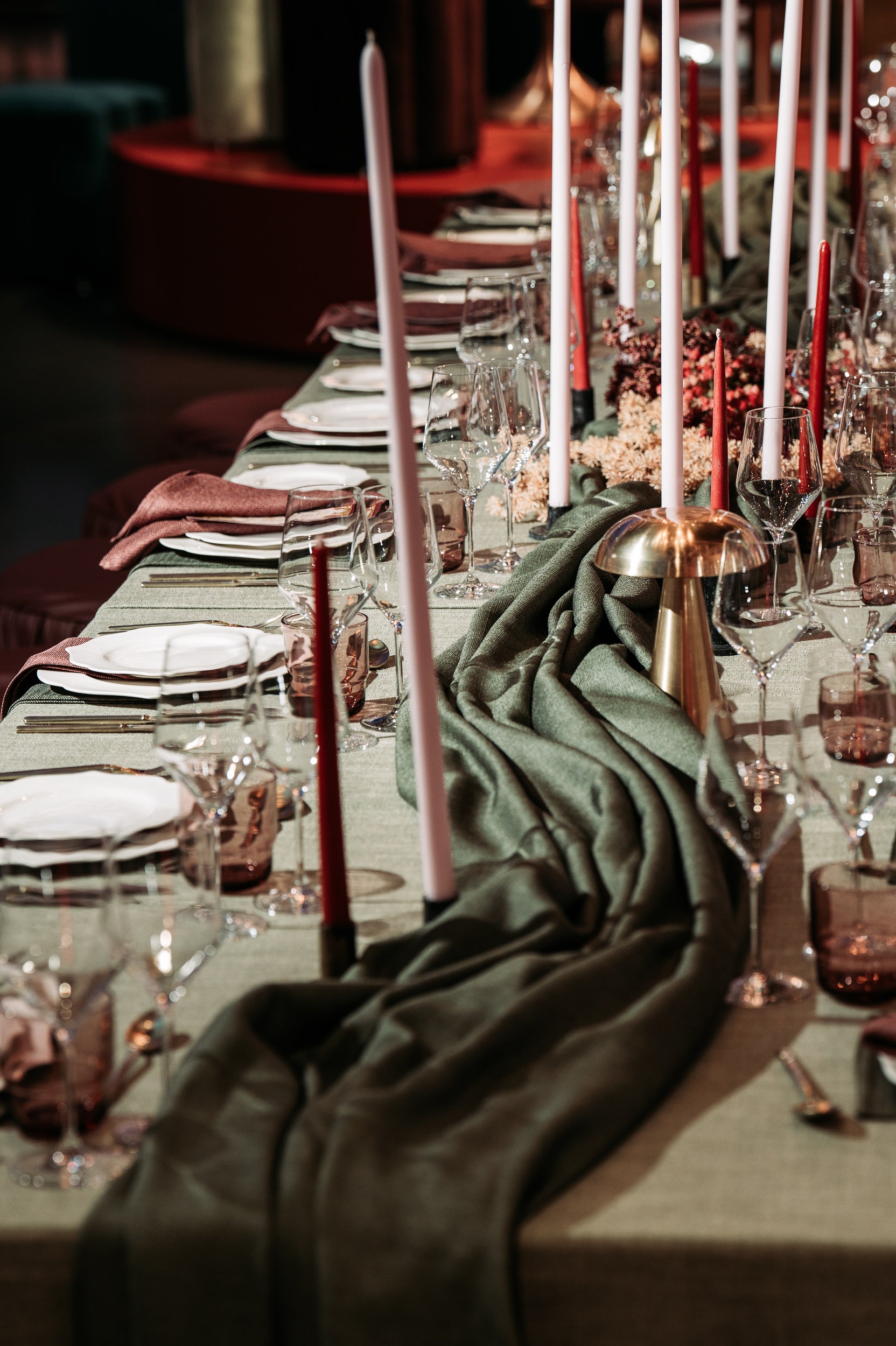 Elegant table setting with green napkins, pink candles, and glassware.