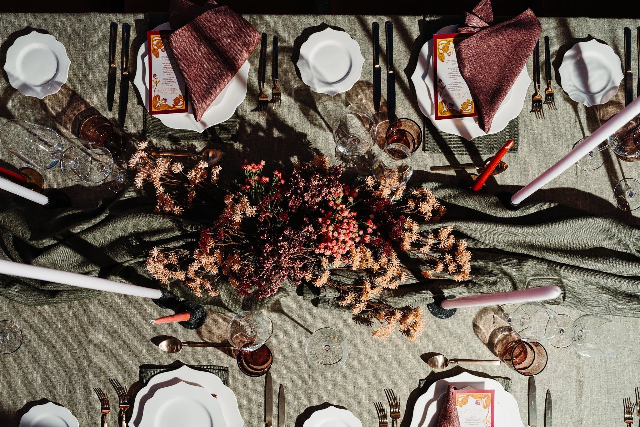 Top-down view of a formally set table with place settings, cutlery, and a floral centerpiece in our Abbotsford Showroom