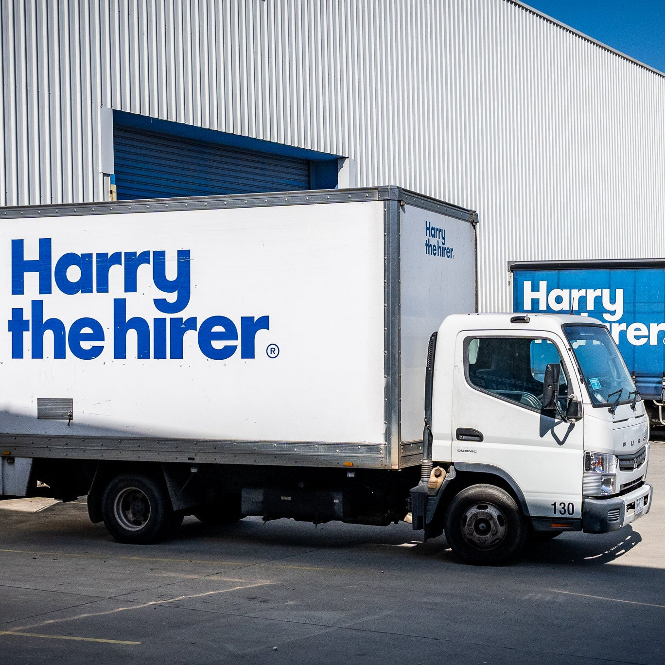 Trucks with 'Harry the Hirer' branding parked outside a warehouse.
