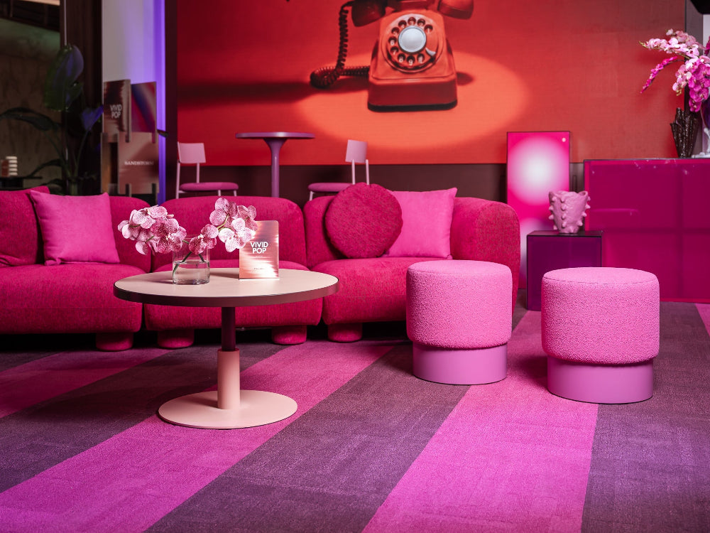 Modern interior with pink furniture and a retro telephone on a red wall.