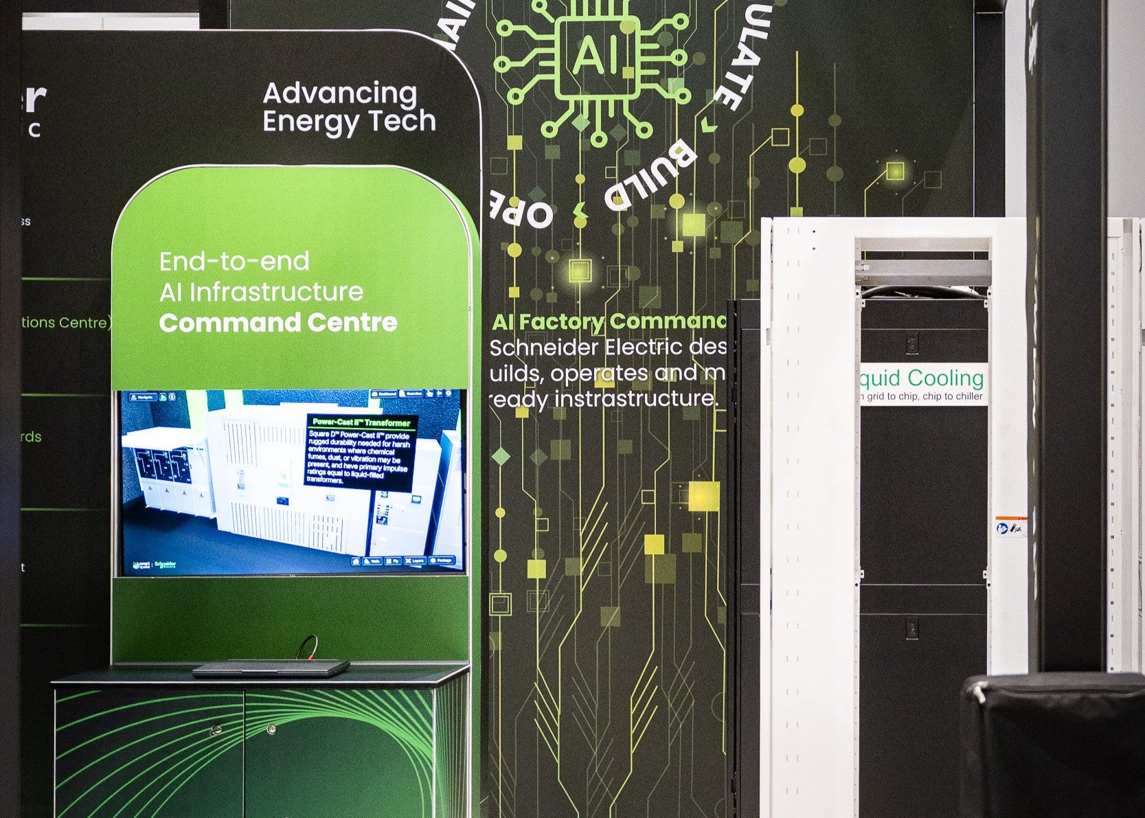 A booth display for Schneider Electric's AI Factory Command Centre, featuring a green and black digital screen, a vertical sign reading 'End-to-end AI Infrastructure Command Centre,' and a white liquid cooling unit with a Schneider Electric Cooling label.