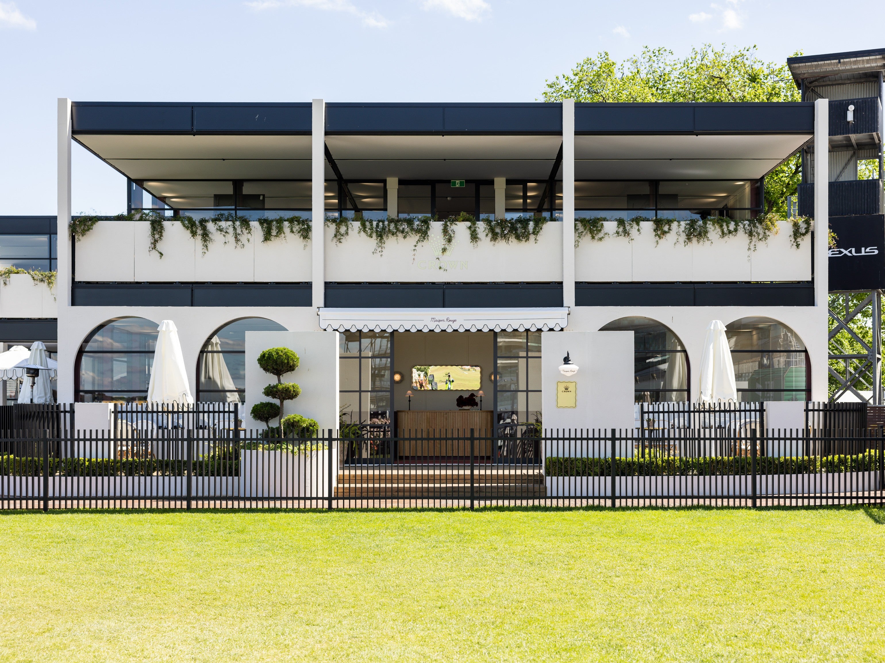 Marquee with greenery on the roof and a well-maintained lawn in front.
