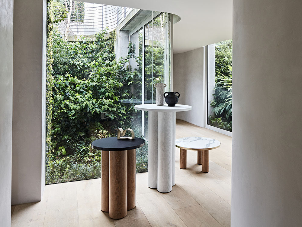 Modern interior with round tables and a view of greenery outside.