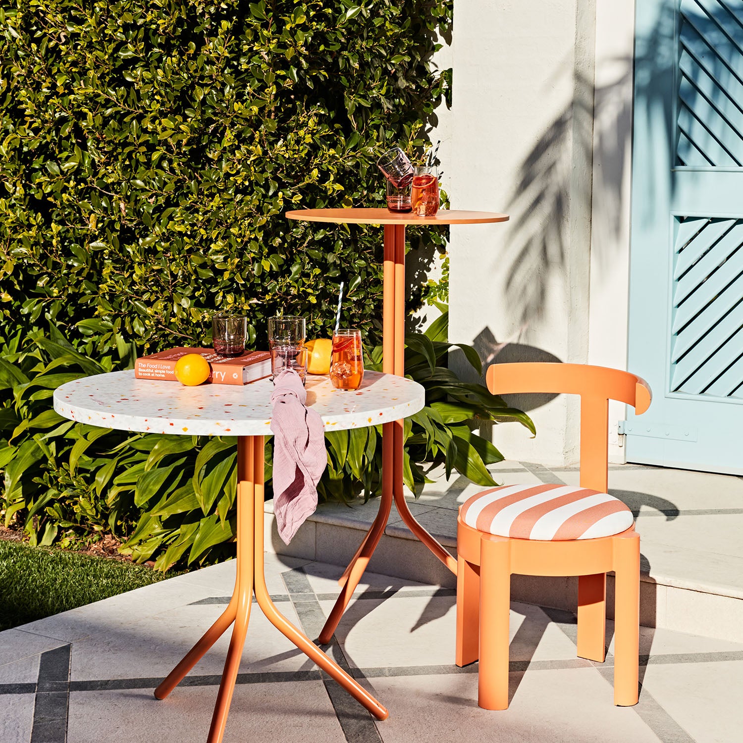 Outdoor setting with a small table and Sunday chair, surrounded by greenery.