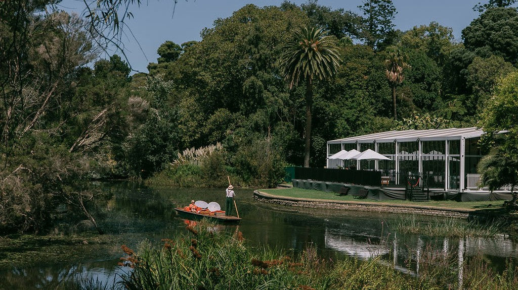Man on a paddle boat near a our Alto Marquee with a lake and trees in the background. Location: Melbourne Botanical Gardens, Melbourne