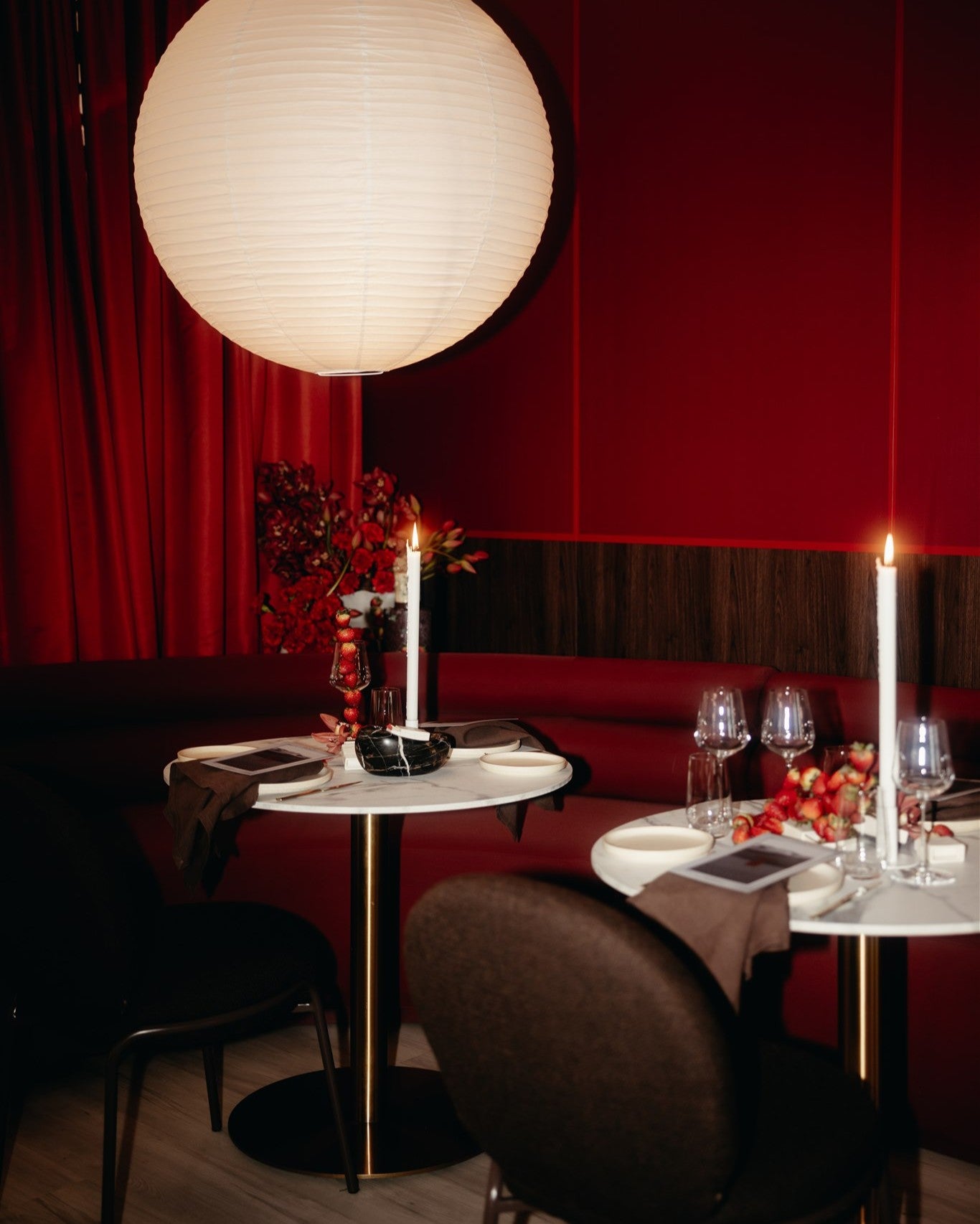 Dining area with red walls, round table, chairs, and decorative elements.