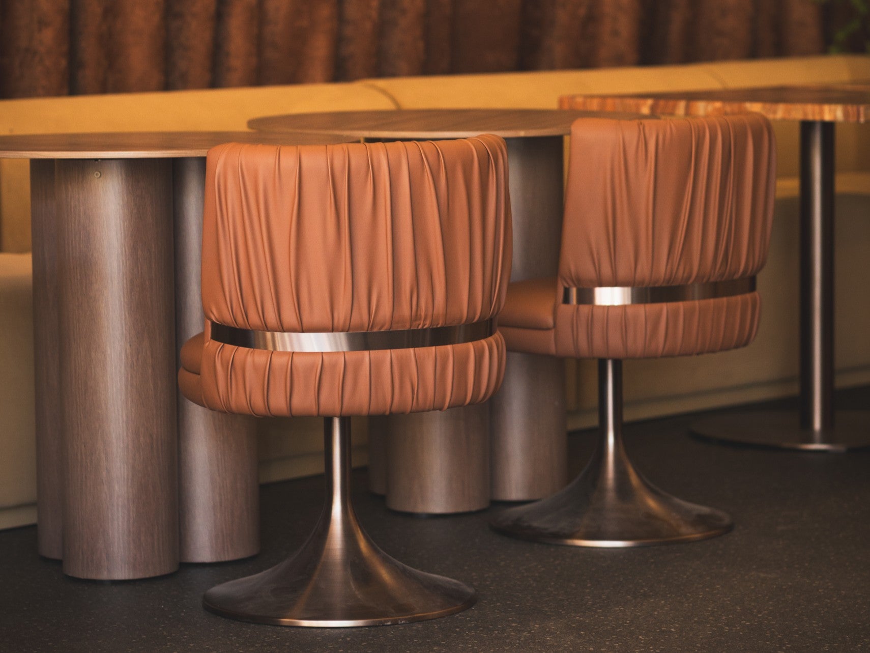 Copper bar stools with metallic finish beneath warm pendant lighting onsite at an event