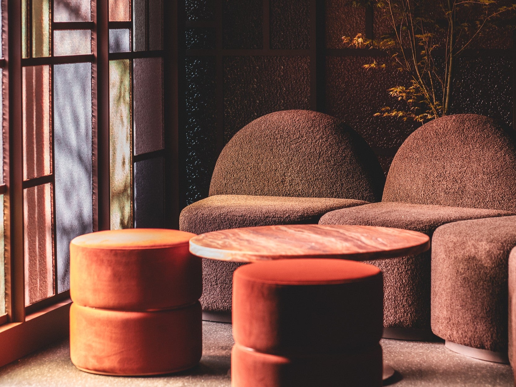 Brown textured chairs and orange stools in a marquee with a window. Onsite at AFL September Club. Our Harper range, Arden Ottomans and Halo Table