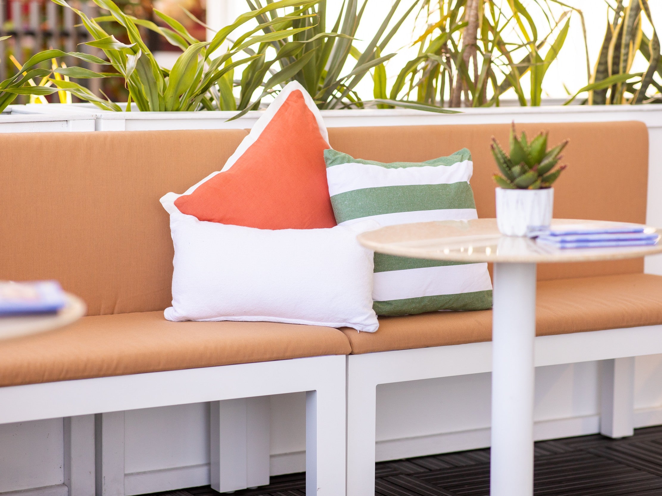 Outdoor lounge setting with orange sofa, cushions and tropical greenery onsite at an outdoor event