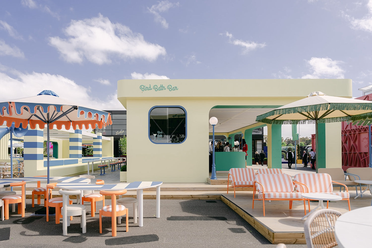 Outdoor seating area with tables, chairs, and a building at Spring Racing Carnival