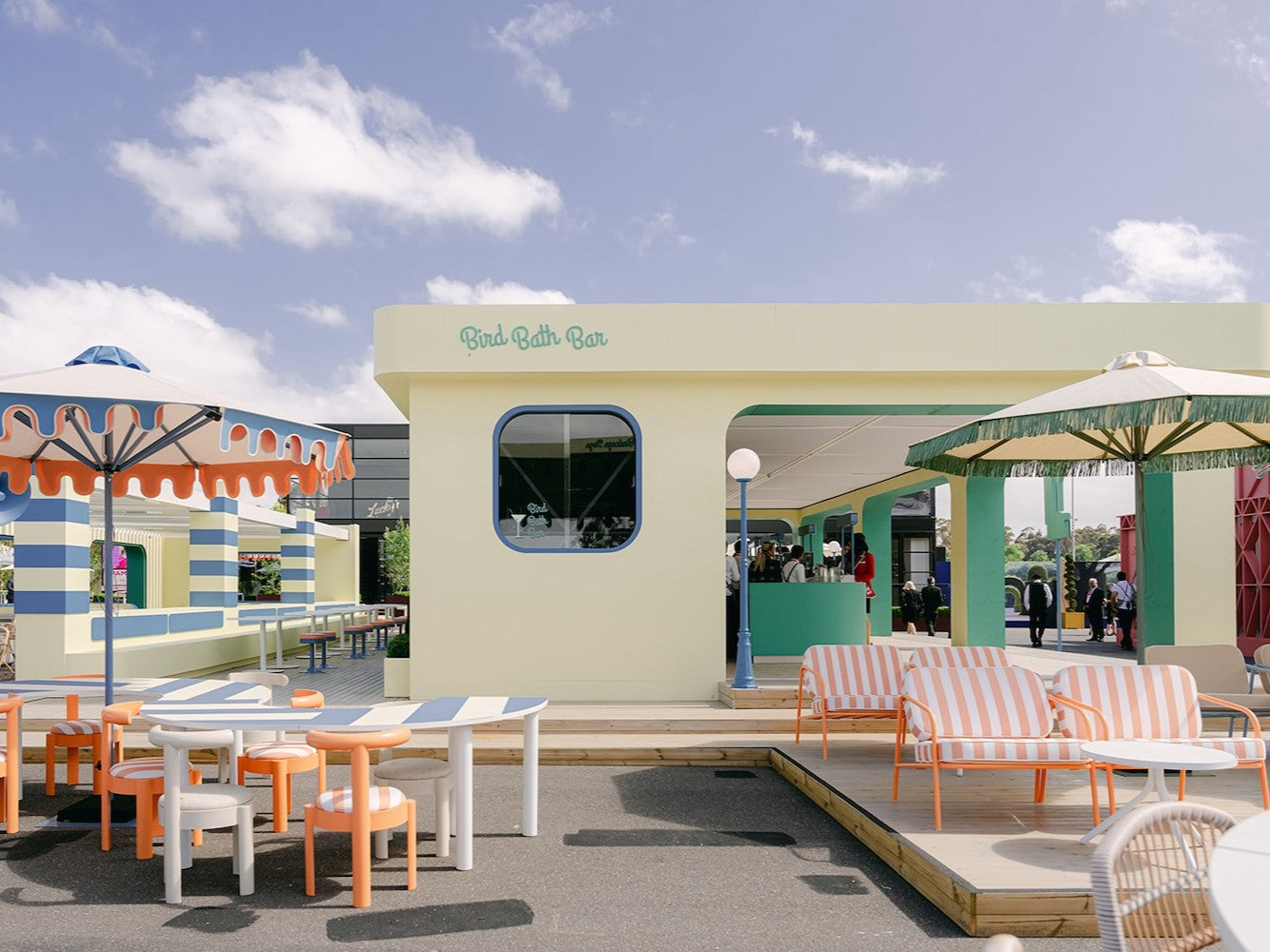 Outdoor seating area with striped furniture and a building in the background. At Spring Racing Carnival