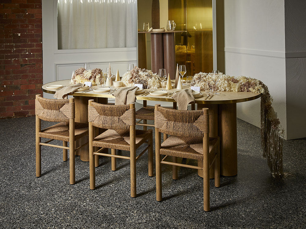 Dining table set with chairs in a room with brick wall and large mirror.