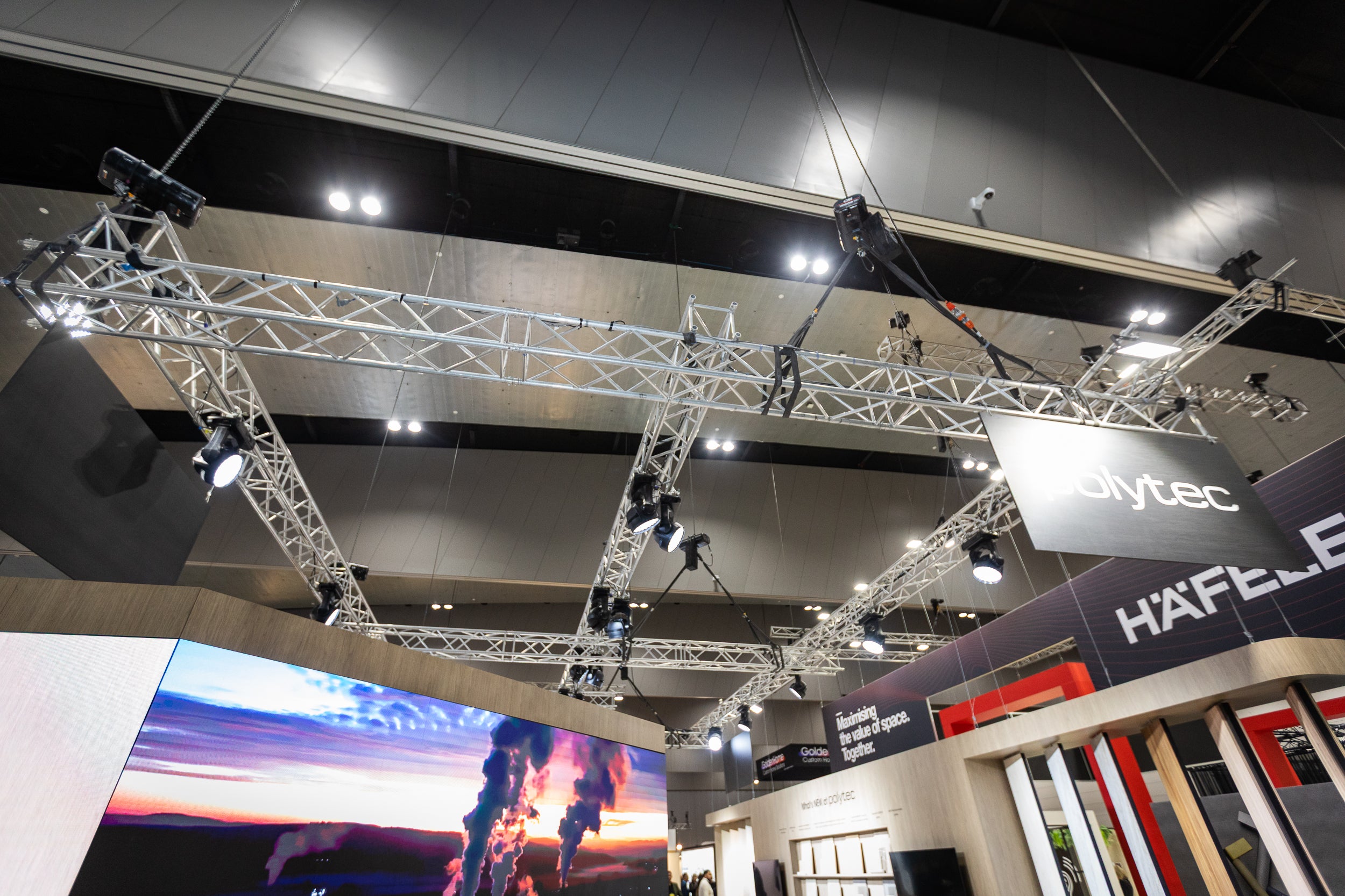Ceiling truss structure with lighting fixtures in a large indoor exhibition hall.