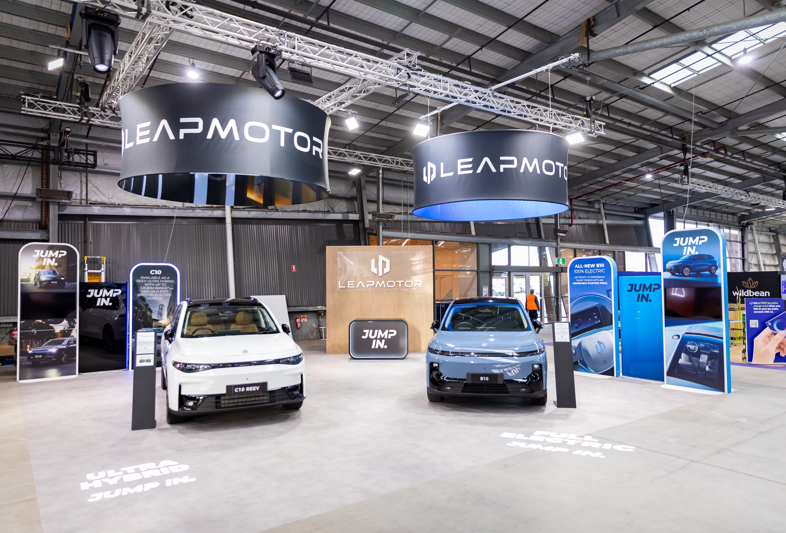 Two electric cars on display at a Leapmotor event with branded booths and signage.