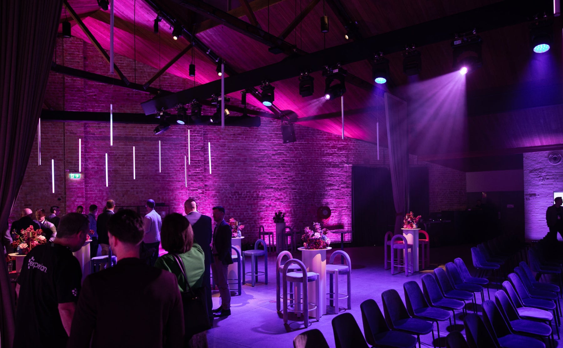 Dining area with purple lighting and people seated at tables.