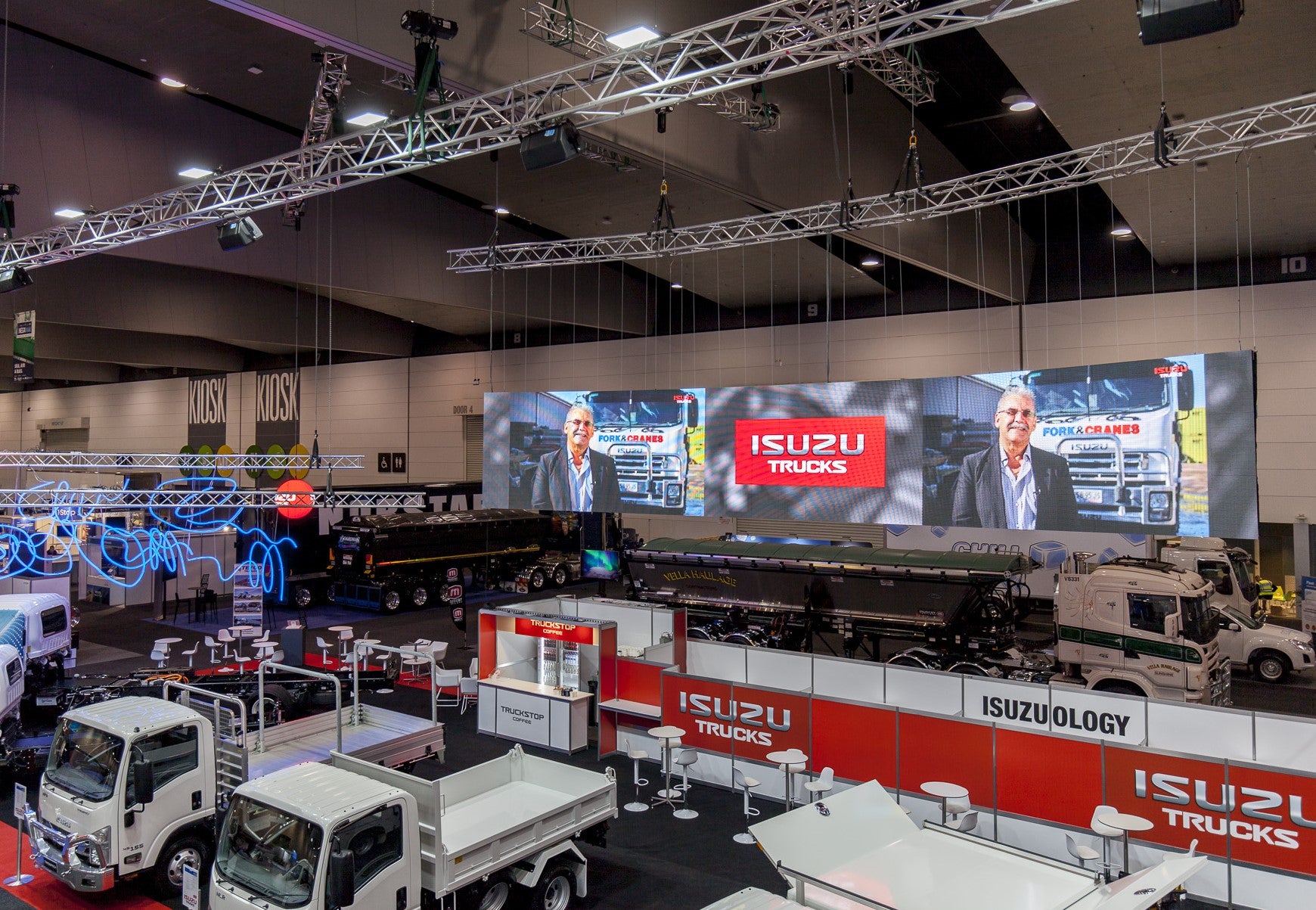Isuzu truck display at an exhibition with large screens and branded booths.