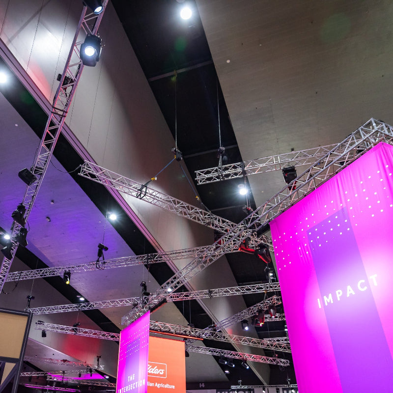 Exhibition setup with pink and purple lighting, visible 'Victoria' branding, and truss structure.