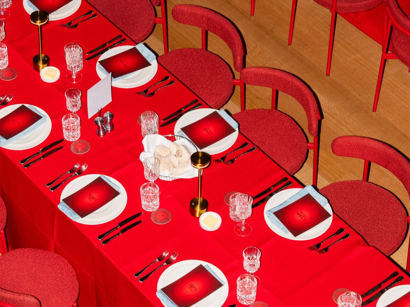 Dining table set with red tablecloth, white plates, red napkins, and Margot red chairs.