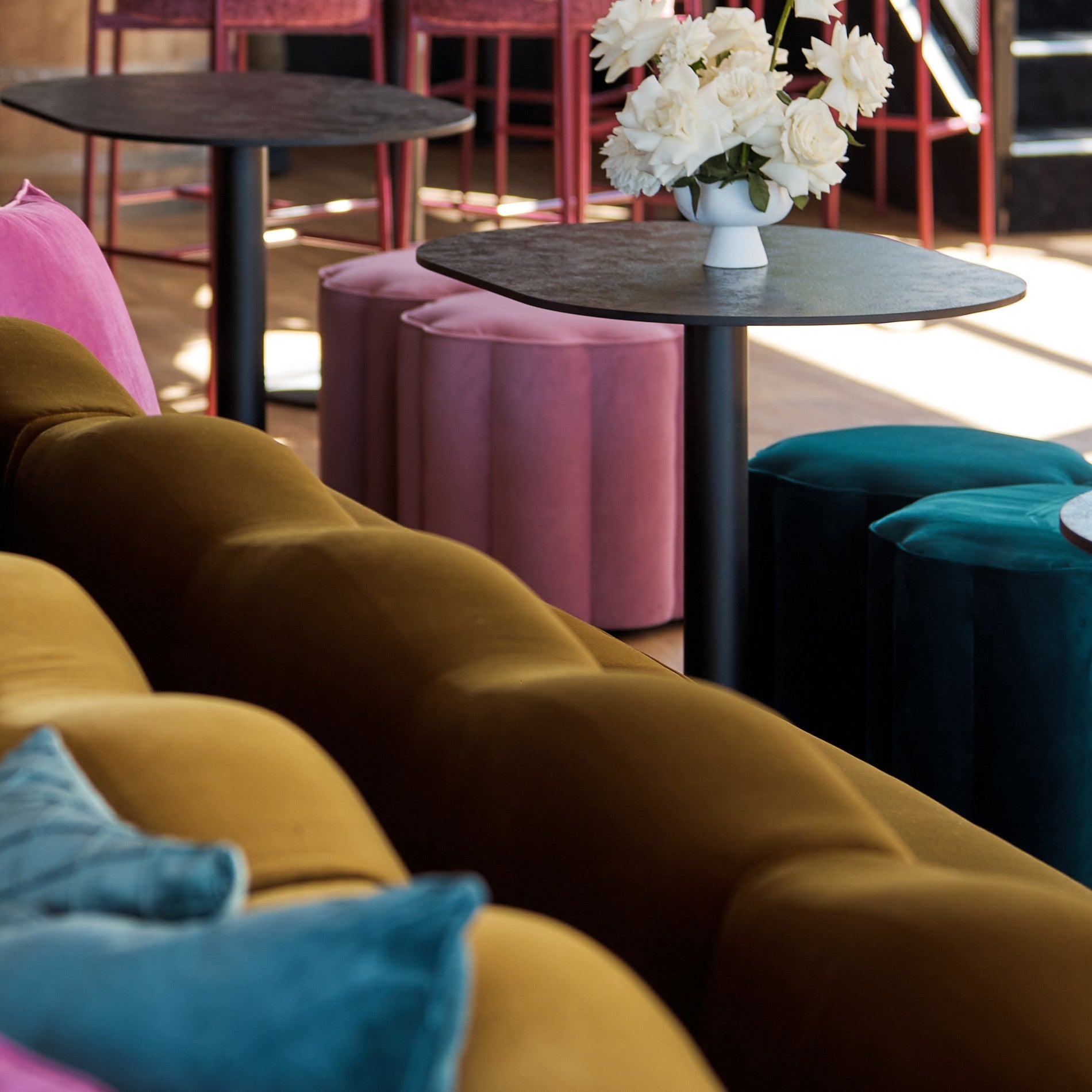 Colorful interior with a Camille sofa, Rosetta stools, and a small round Halo table with flowers.