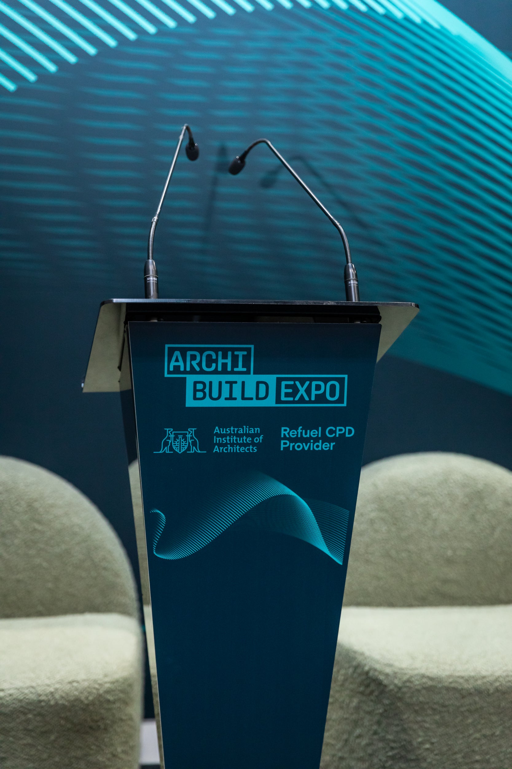 Blue podium with 'ARCHI BUILD EXPO' branding in a conference setting