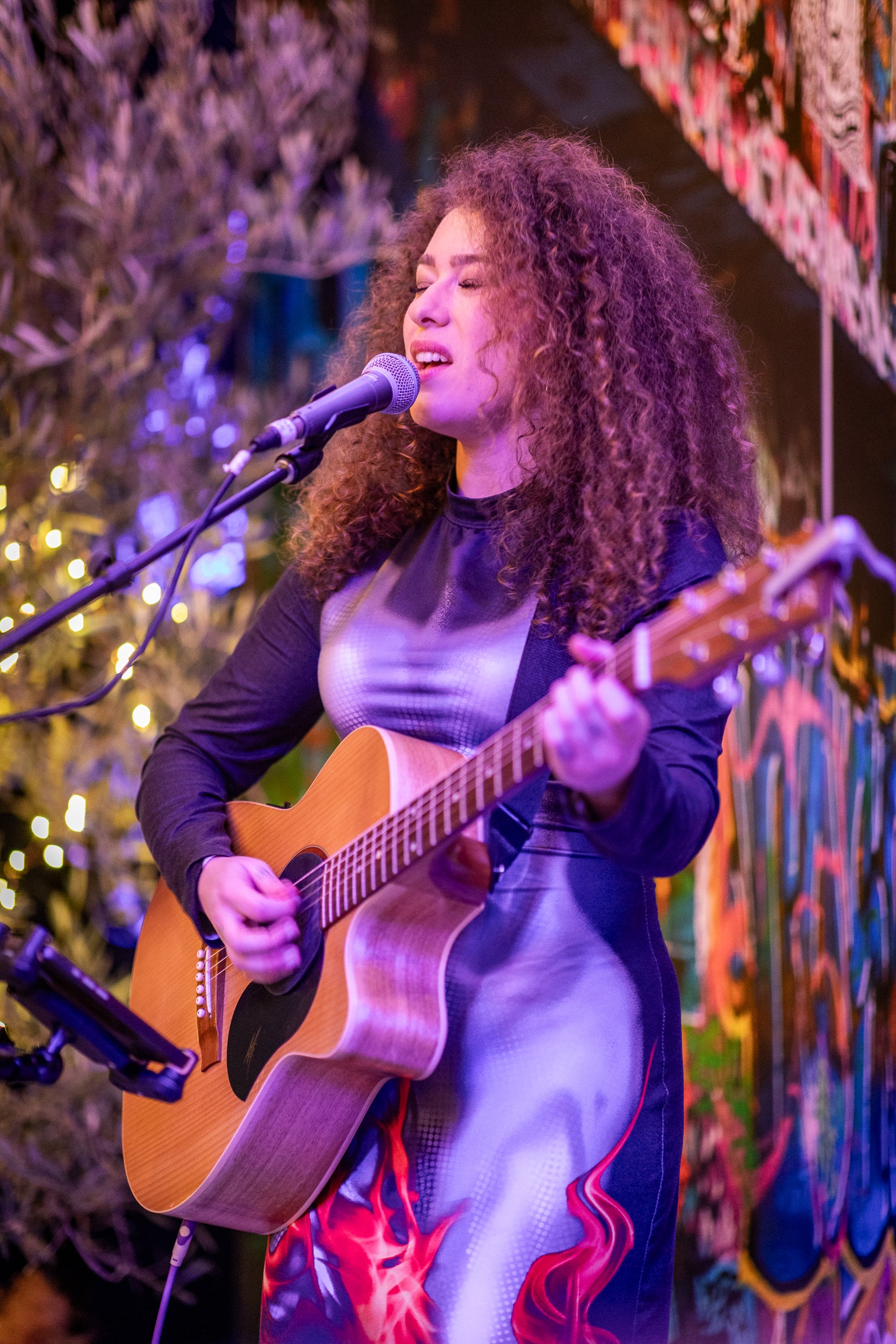 Person playing guitar and singing into a microphone with a festive background. At a Logitech Showcase event in Melbourne.