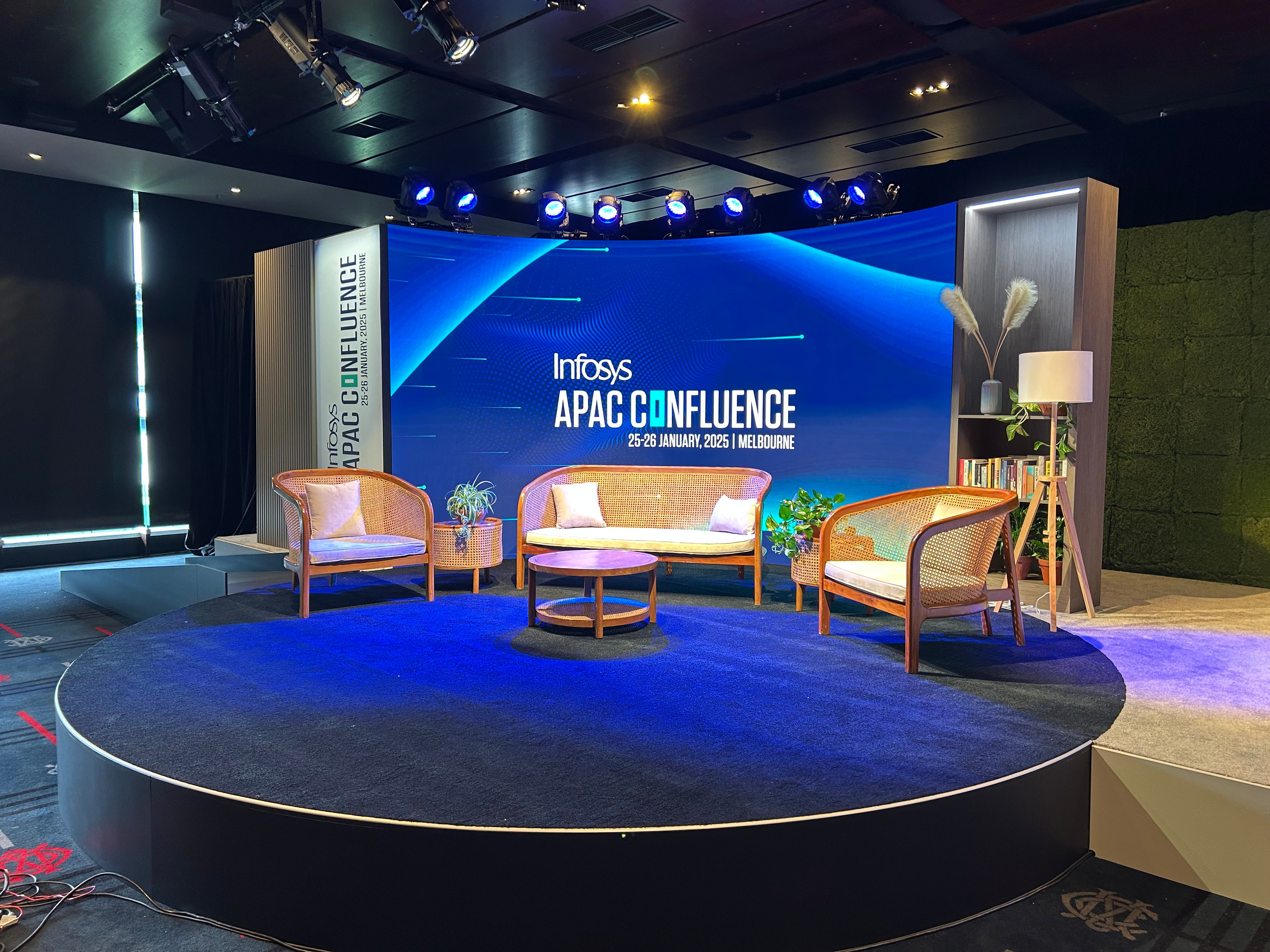 Stage setup with chairs and a large screen displaying 'Infosys APAC Confluence' event.