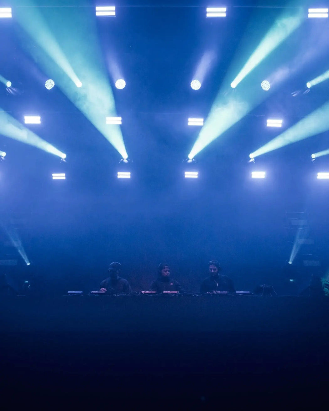 Three people on a stage under blue and green stage lights