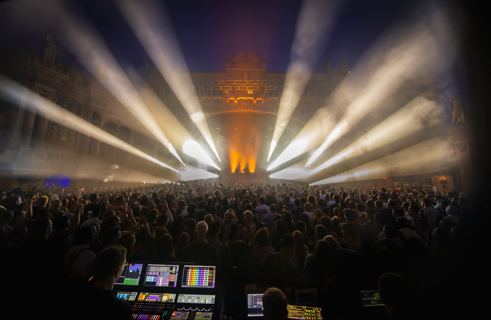 Large indoor event with stage lights and a crowd, possibly a concert or festival.