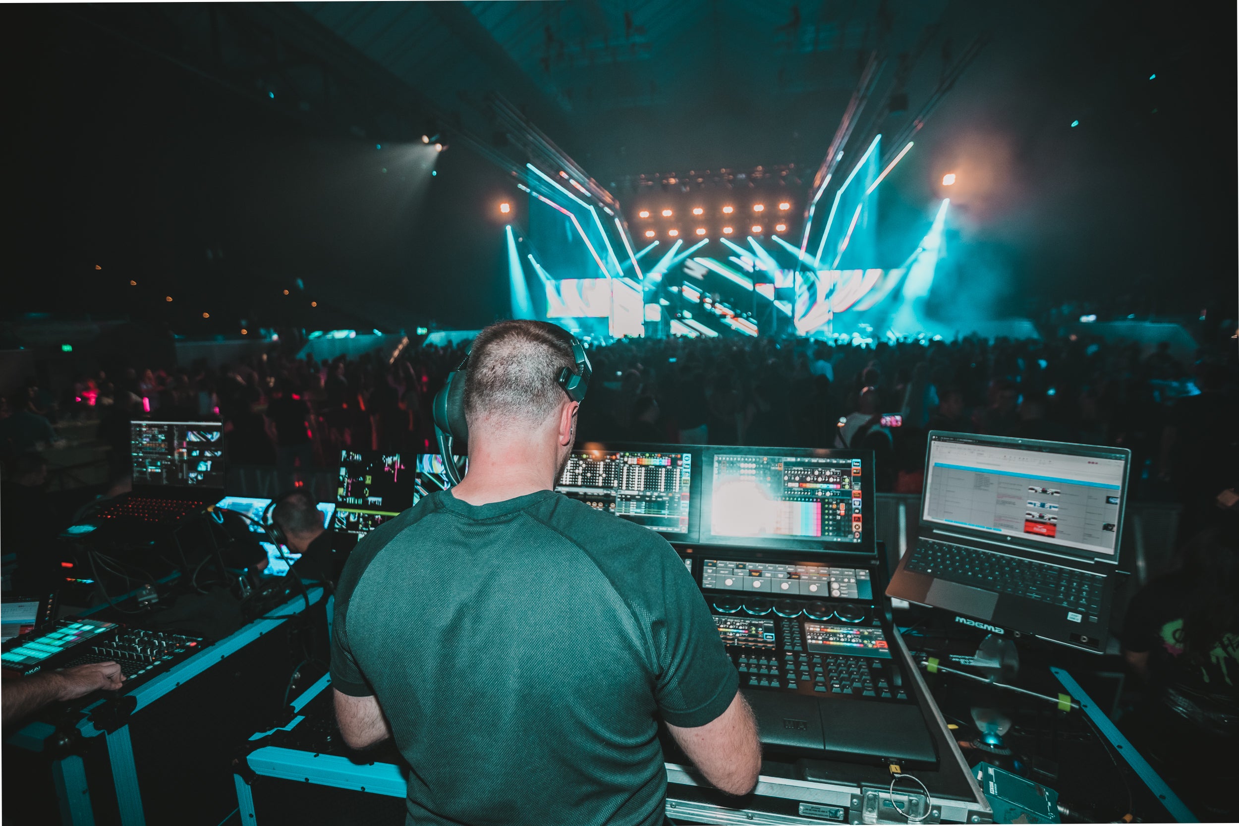 DJ at a music event with equipment and crowd in the background