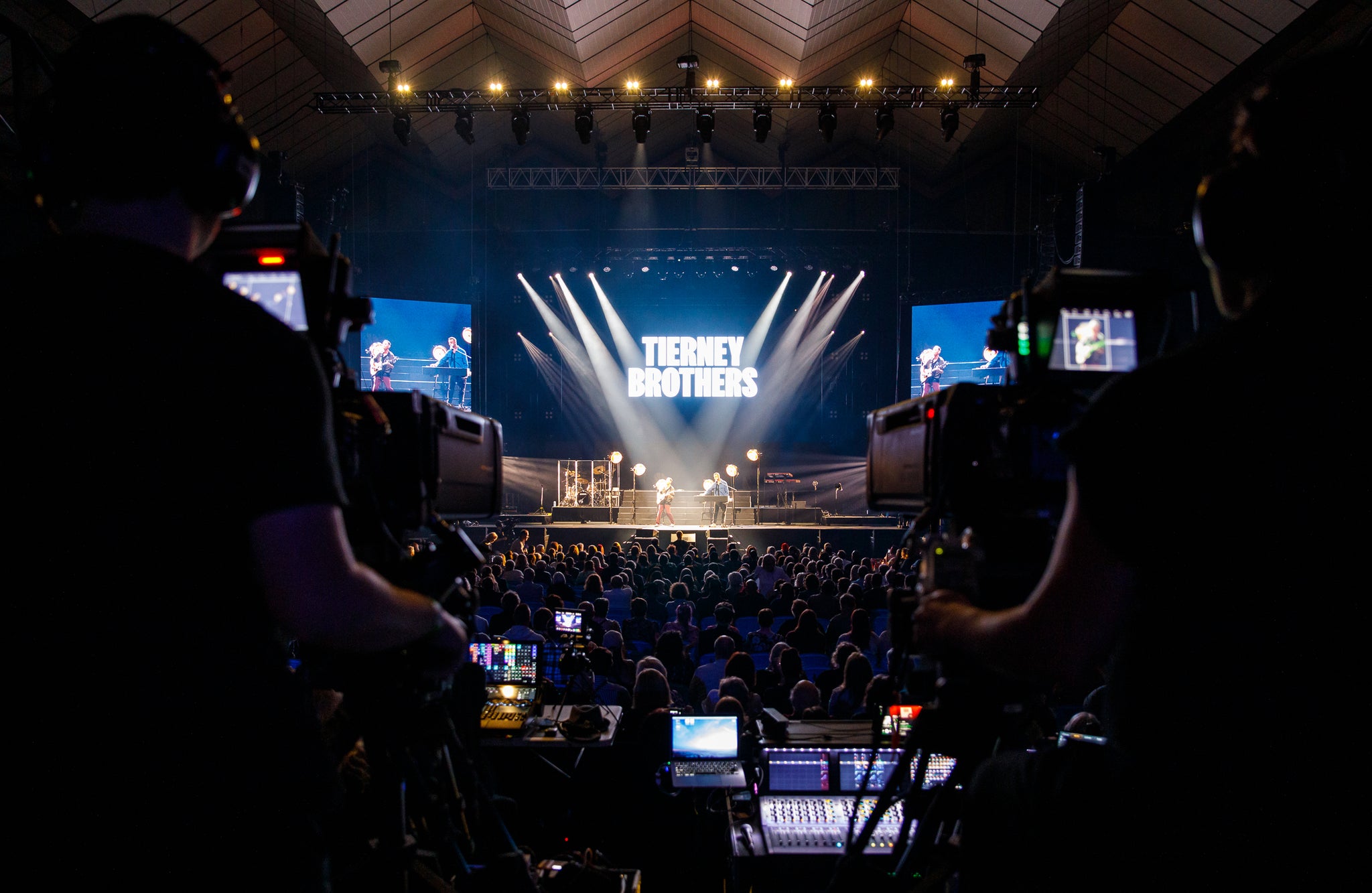 Stage with 'Tierney Brothers' branding, audience, and camera equipment.