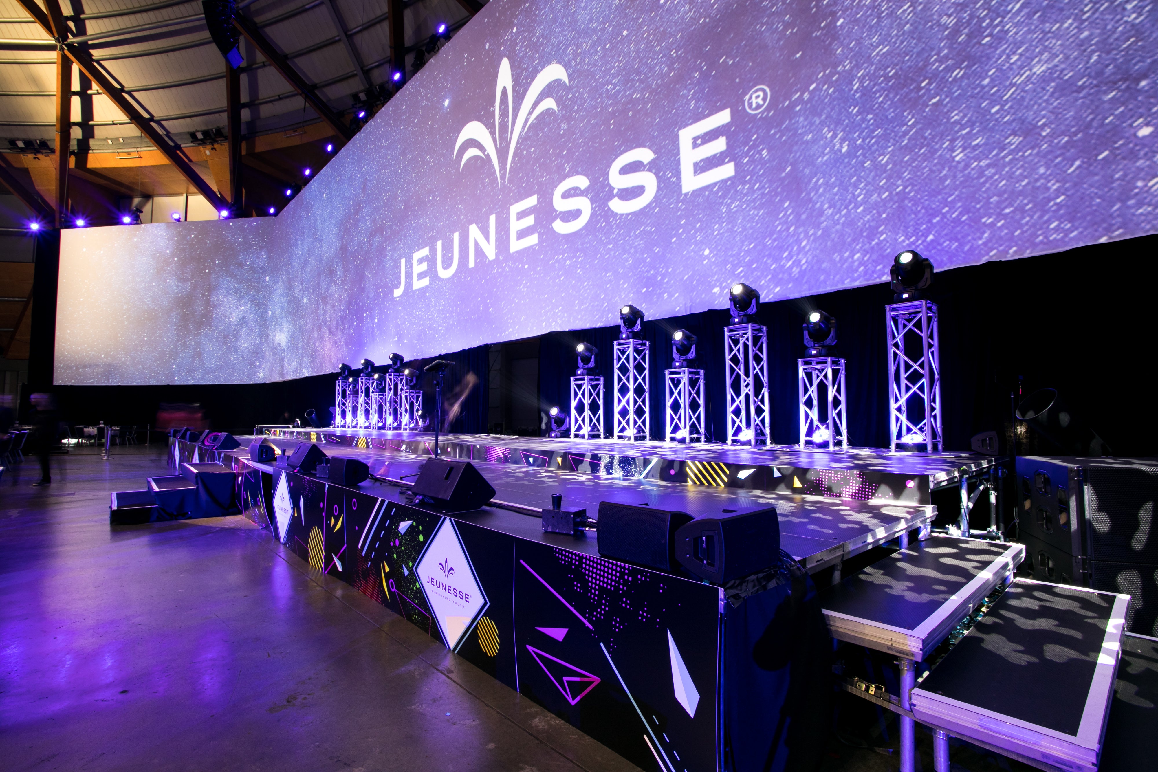 Event setup with 'Jeunesse' branding on a large screen in a large hall.