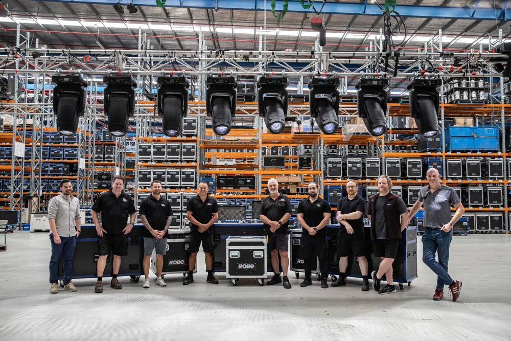 Group of people standing in a warehouse with ROBE lighting equipment