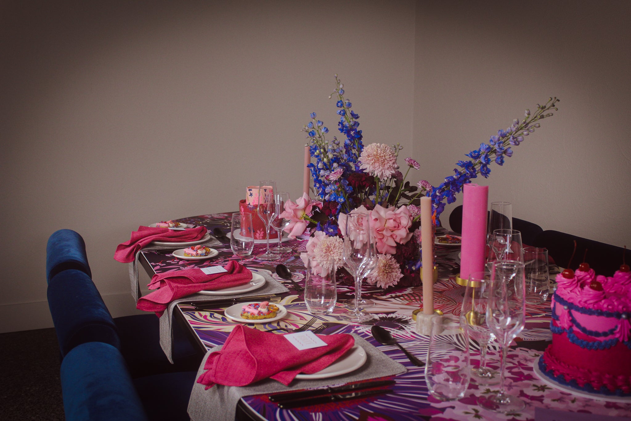 Decorated table with flowers, candles, and a cake in a room.