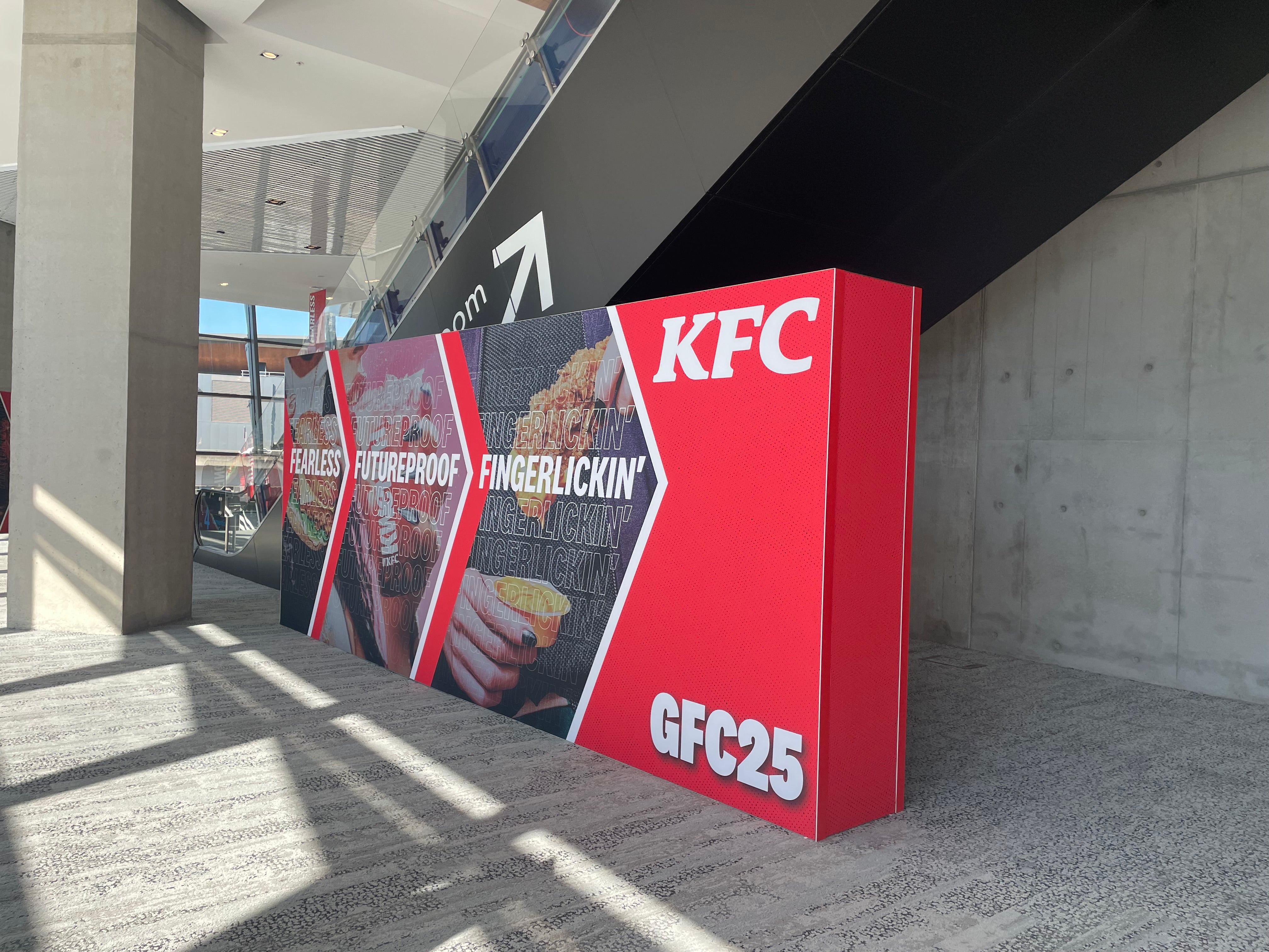 KFC promotional standee with images and text in an outdoor setting
