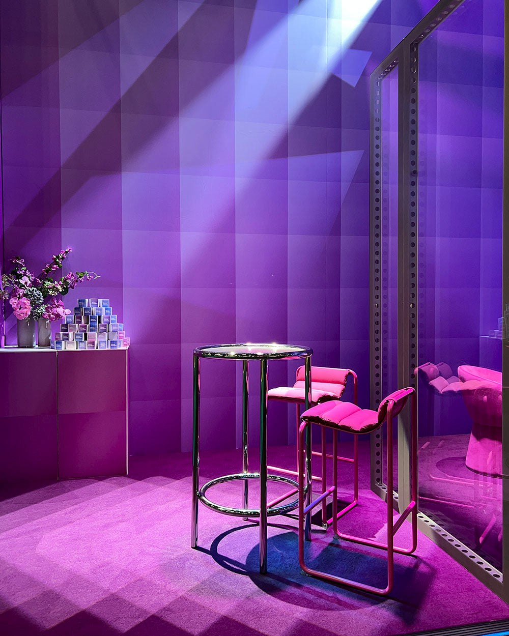 Expo stand with purple walls, pink chairs, and a bar counter.