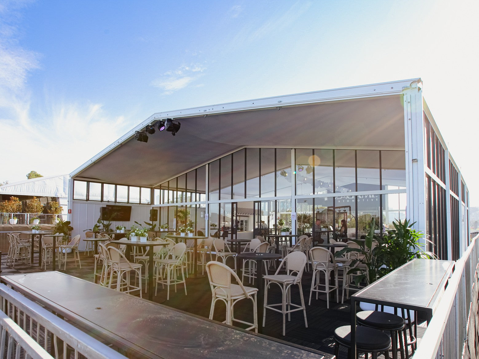 Outdoor marquee space with tables, chairs on a clear day. Taken at Grand Prix.