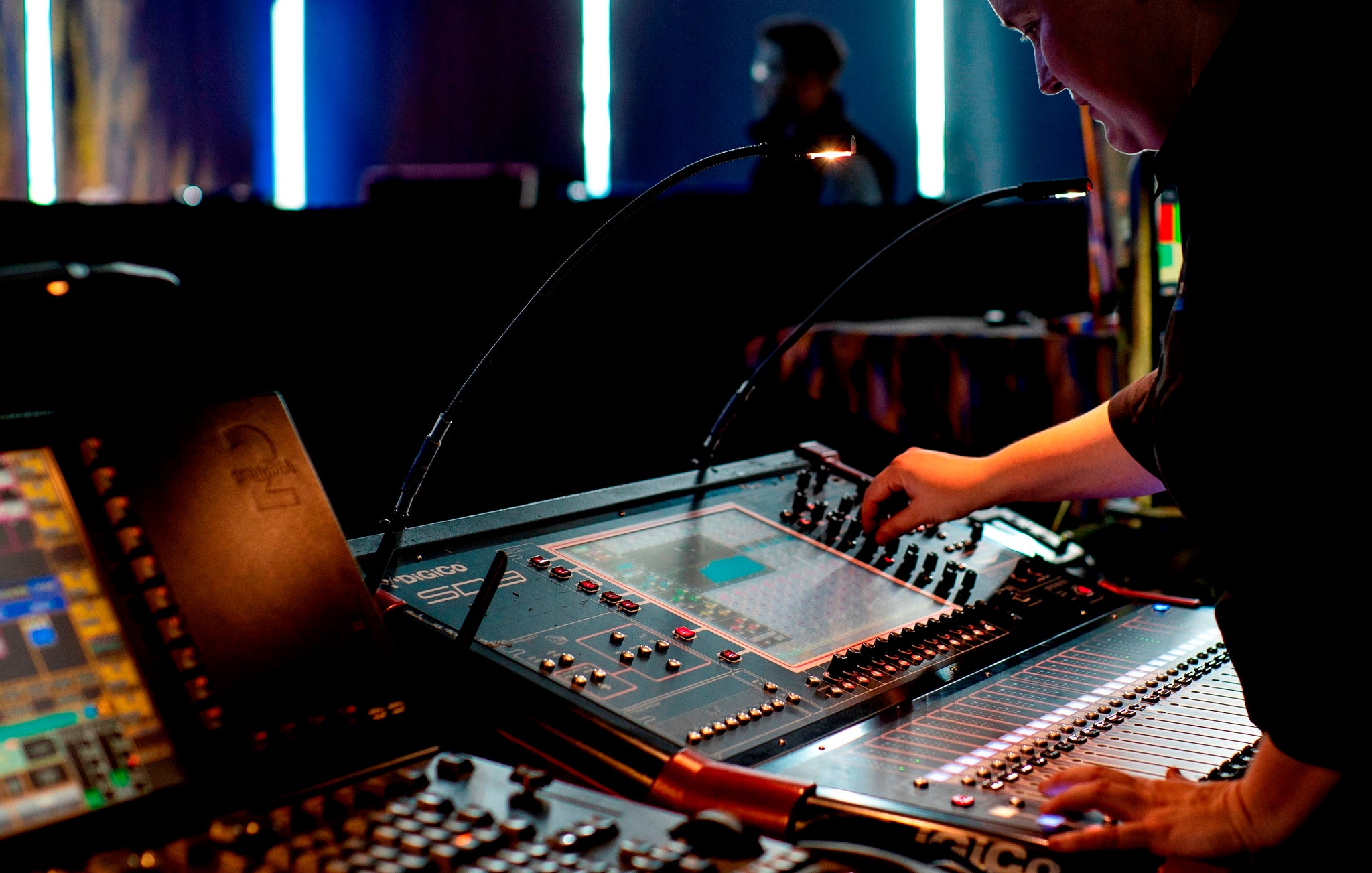 Person operating a sound mixing console in a dimly lit room