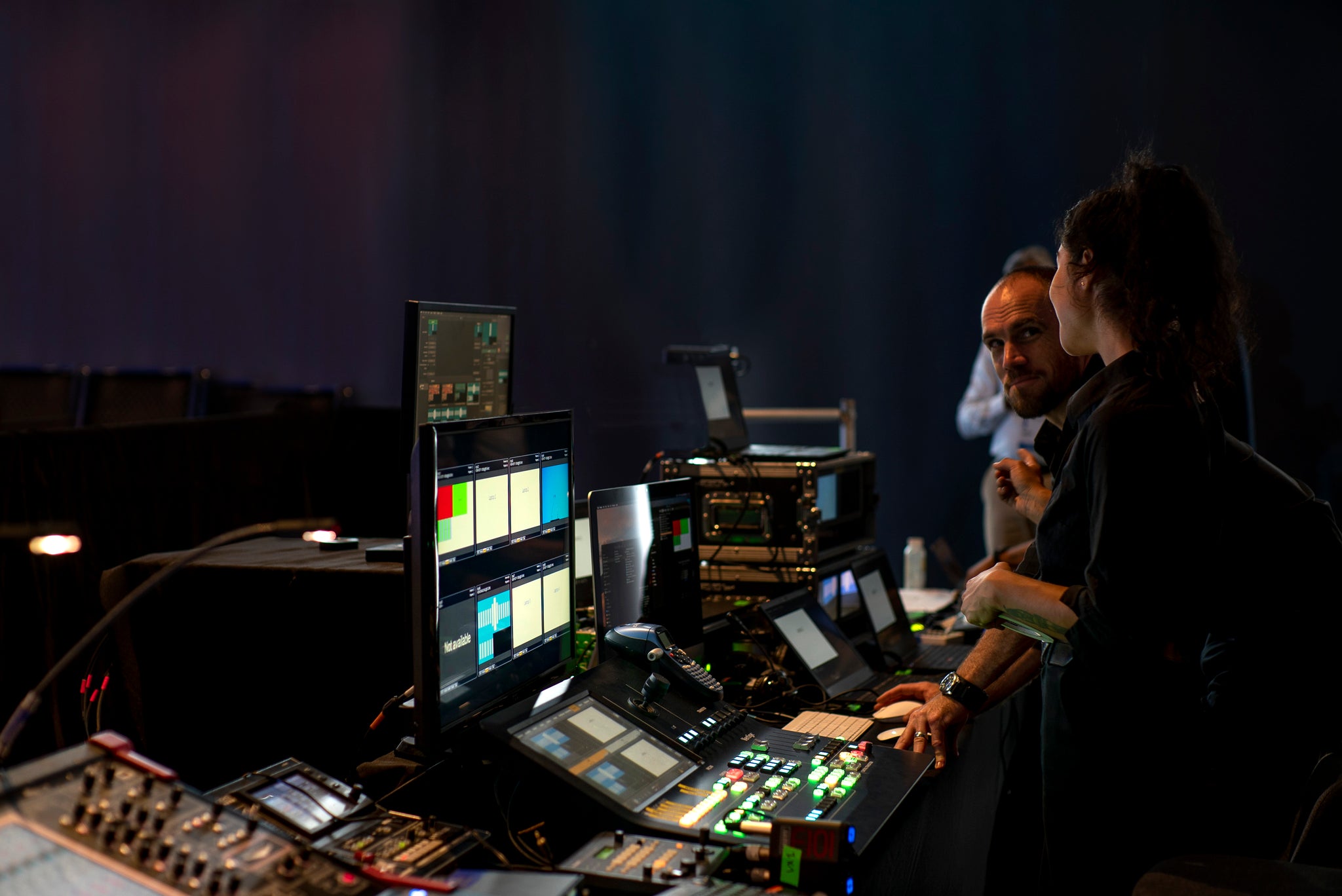 Two people working with audio and video equipment in a dark room