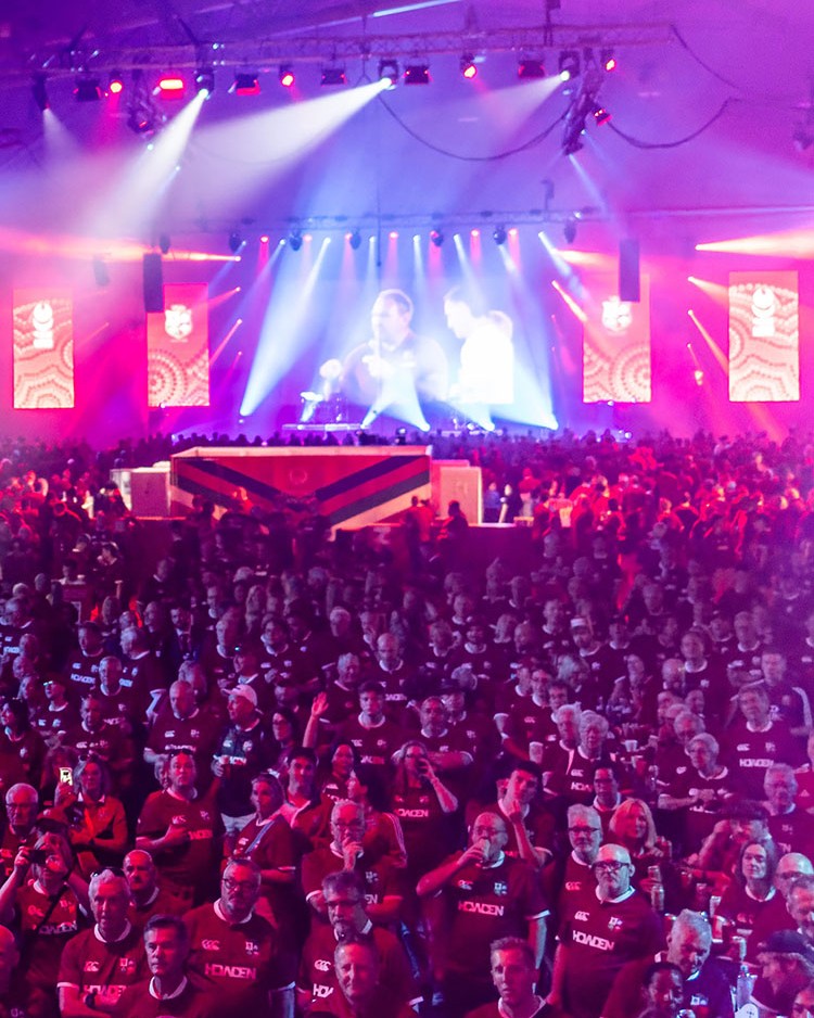 Large crowd at a sporting event, with red and purple lighting over the hall