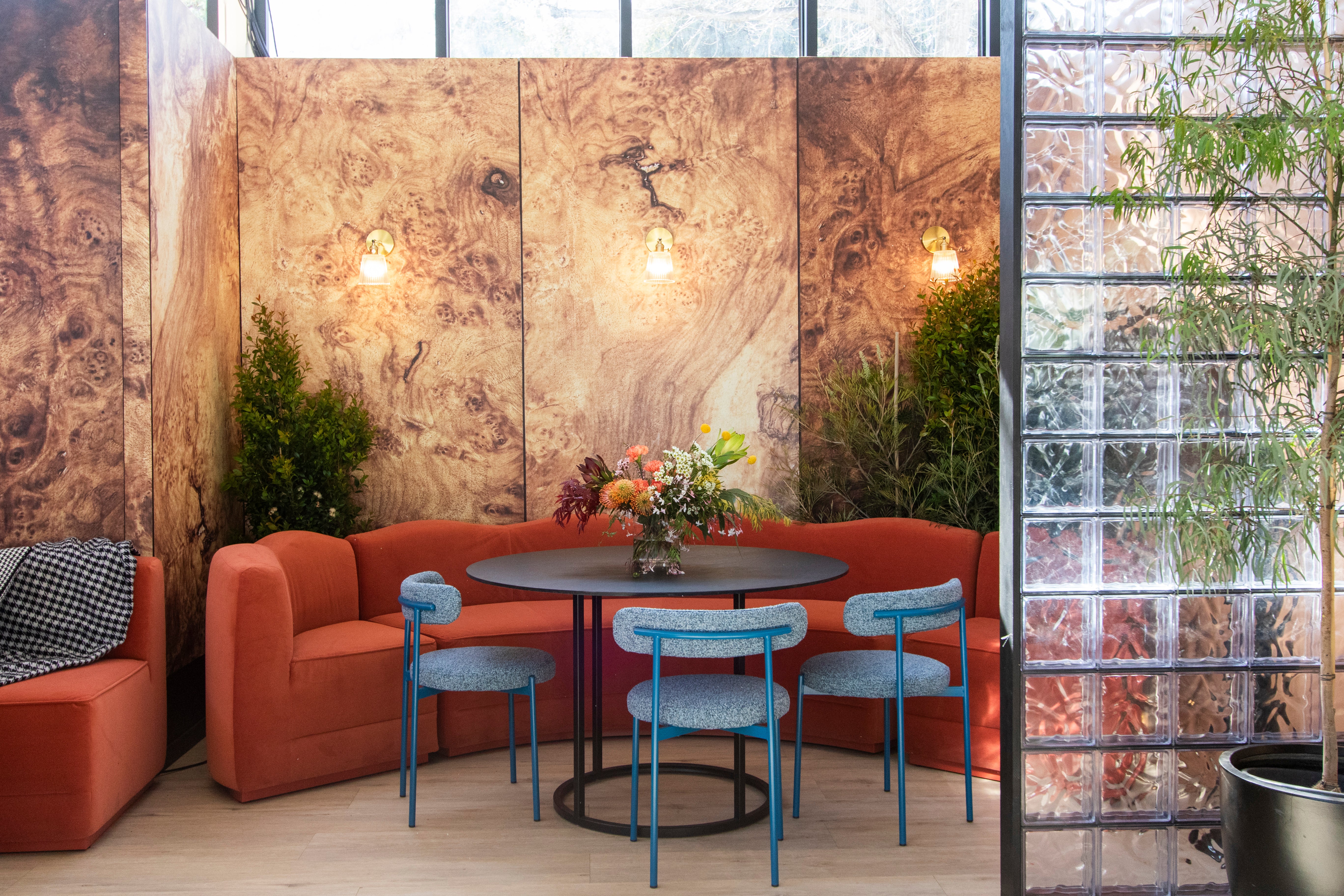 Modern interior with red sofa, blue chairs, and a round table against a textured wall.
