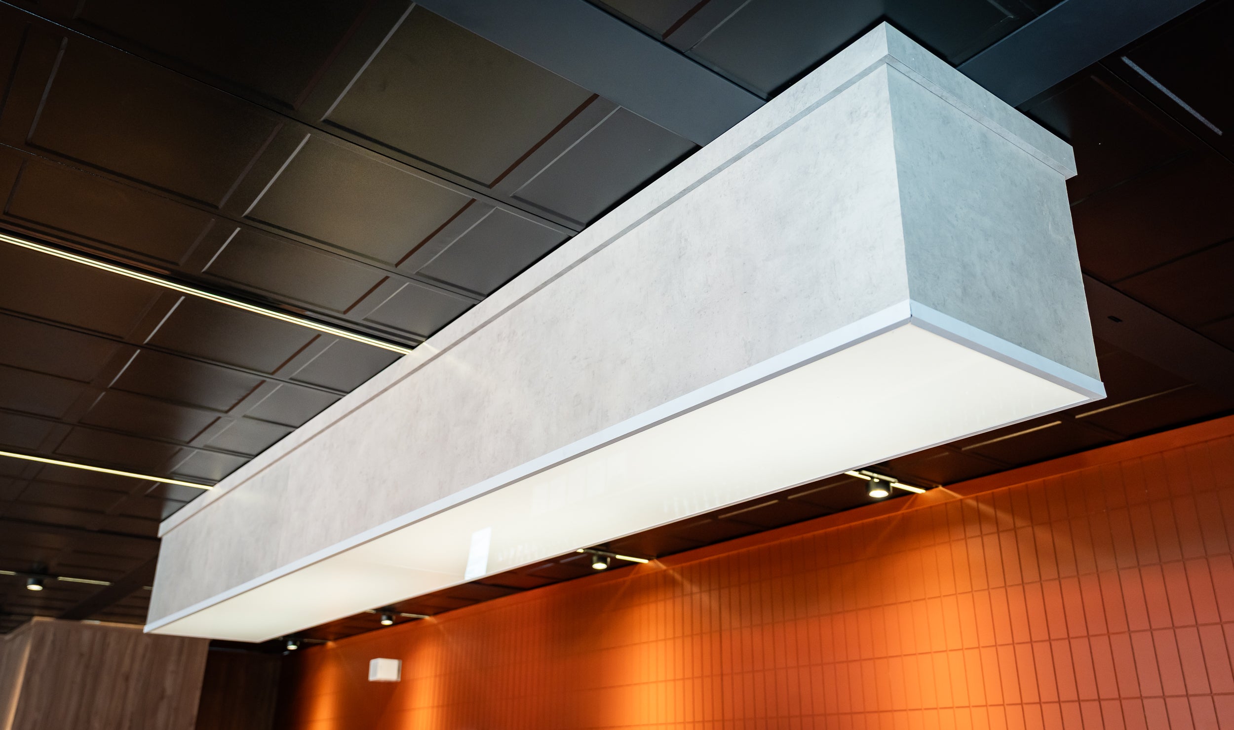 Modern ceiling light fixture in a room with orange walls and wooden paneling.