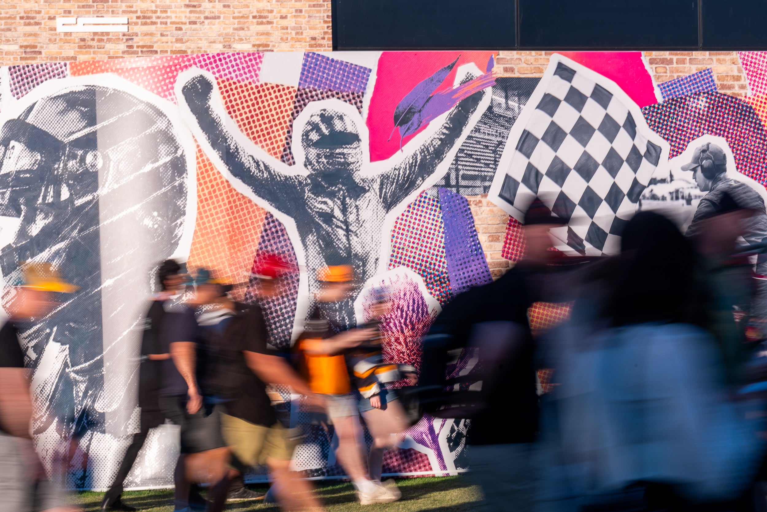 People walking past a large colorful mural with abstract designs and figures on the side of a Highline structure