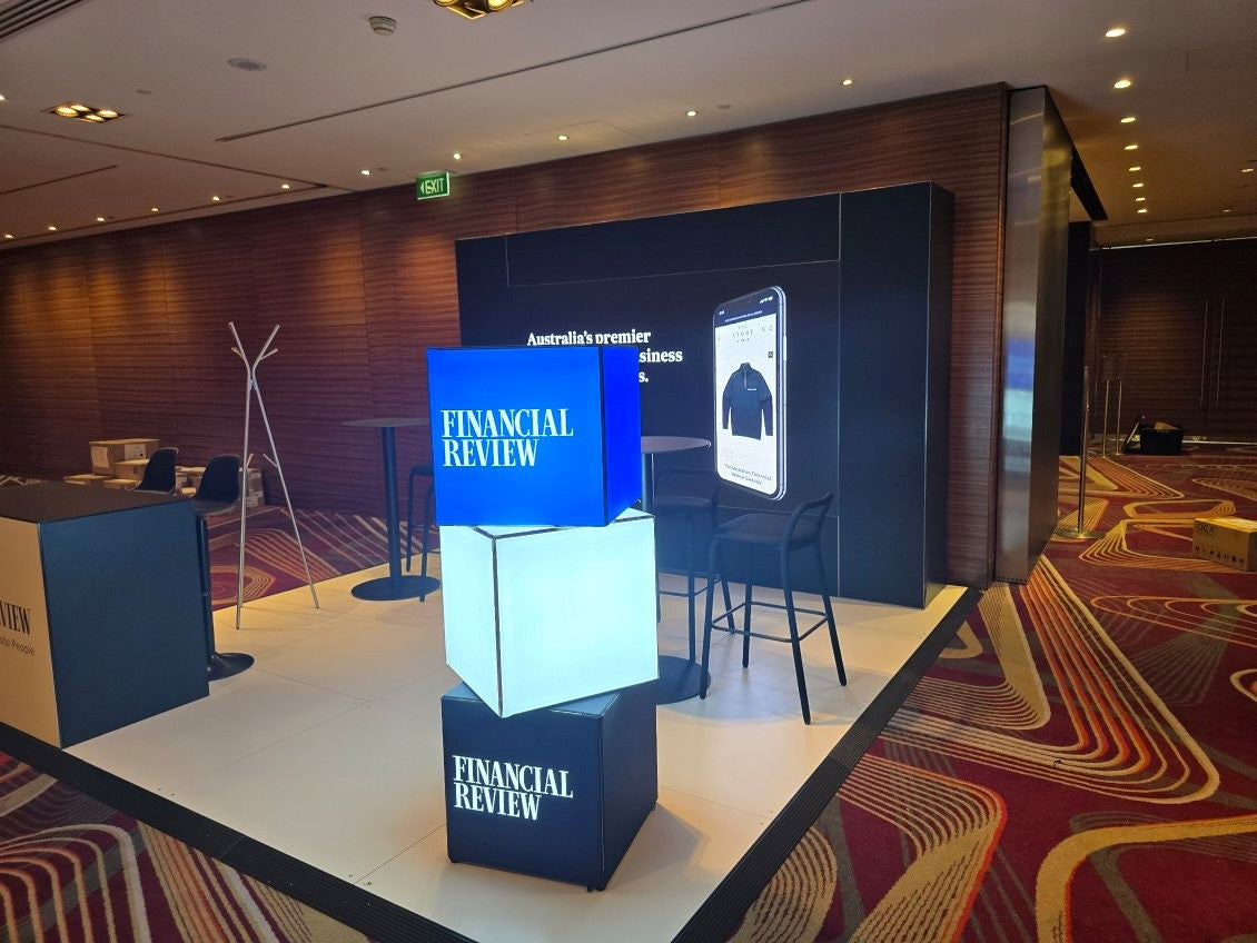 Display stand with 'Financial Review' branding in a room with chairs and tables.