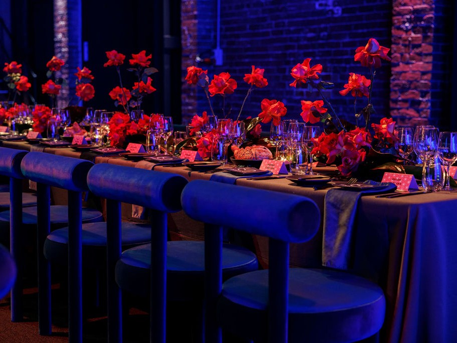 Decorated table with red flowers and candles in a dimly lit room. Featuring our totem chair.