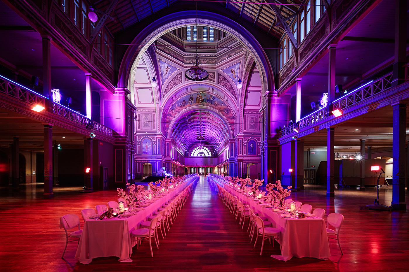 Long table set for a formal event in an elegant, large hall with purple lighting. Taken at the Royal Exhibition Building in Melbourne