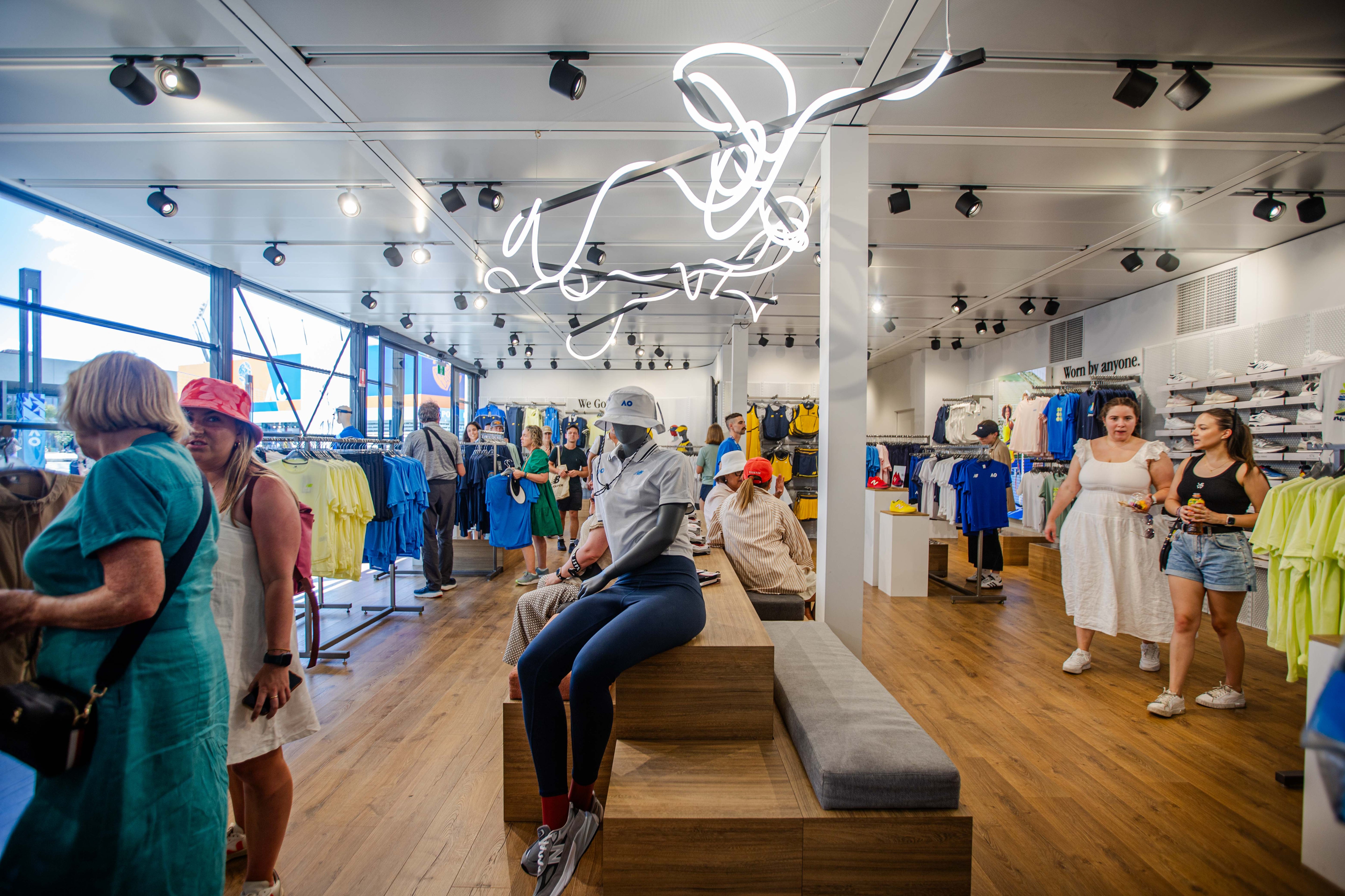 Interior of a temporary store with customers and staff, featuring a prominent neon sign.