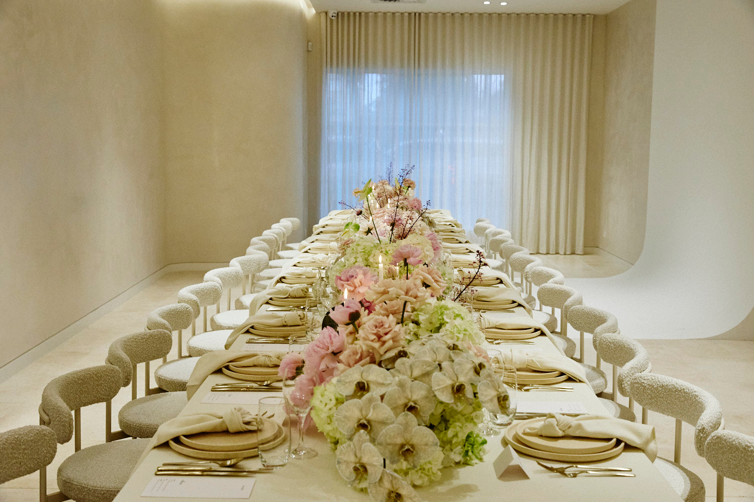 Elegant dining table set up with floral centerpieces in a modern room, featuring our Margot Chairs.