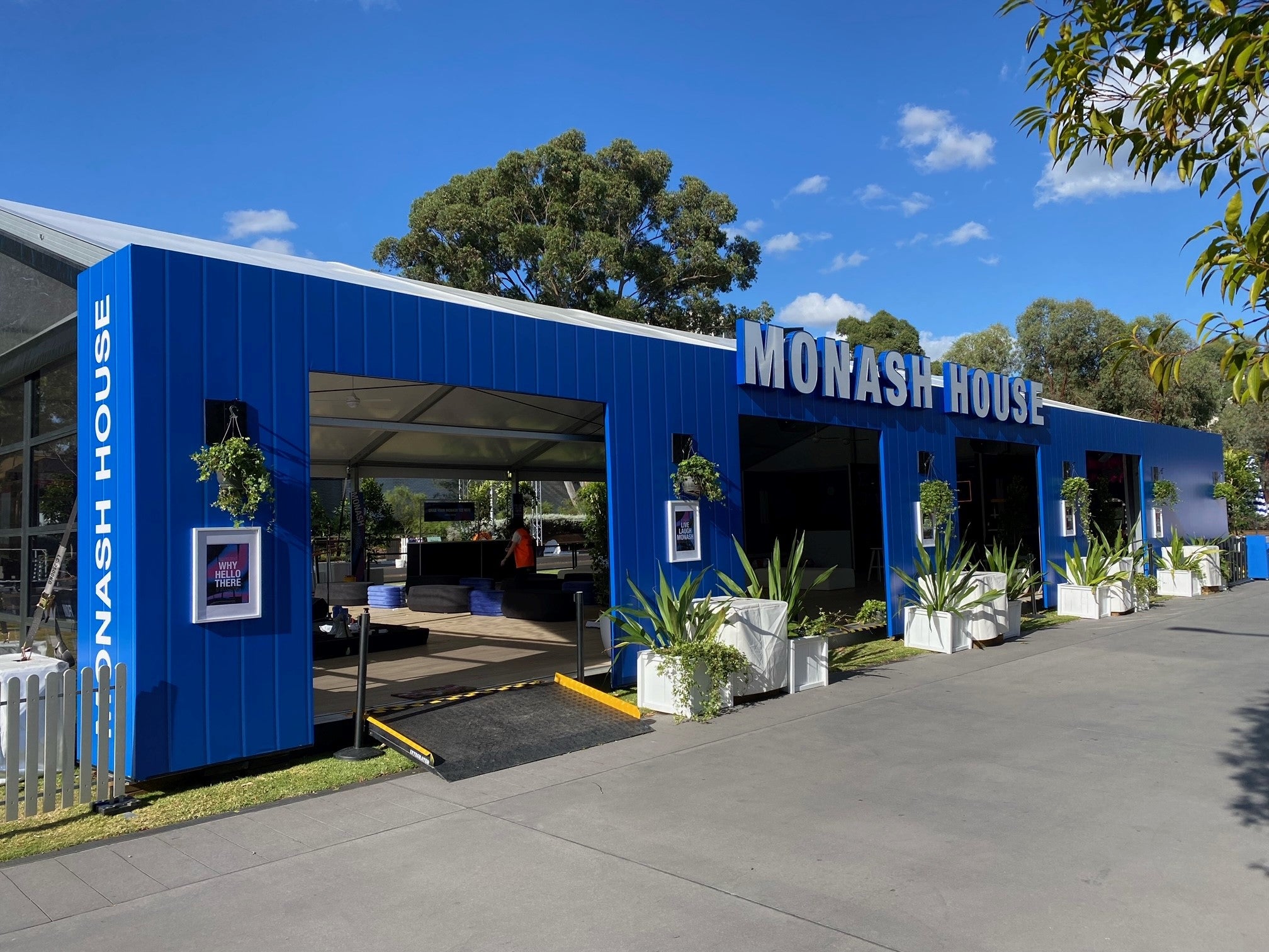 Blue building with 'Monash House' branding on a sunny day.