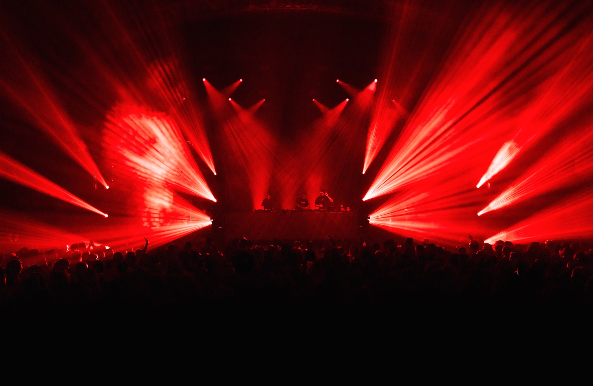 Red laser lights on a dark stage with audience silhouettes